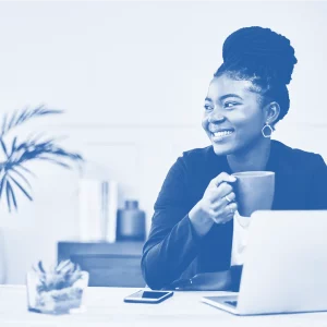 african american woman drinking coffee at her computer while smiling