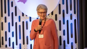 Alice Garland, former SECU Board of Directors member, holds a microphone while speaking on stage.